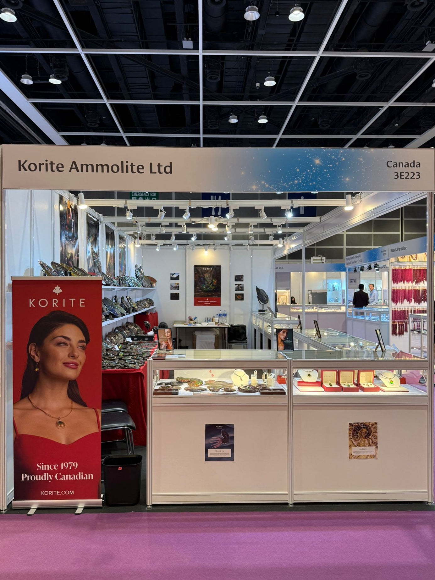 Korite Ammolite Ltd booth at a trade show with jewelry display cases and promotional materials.